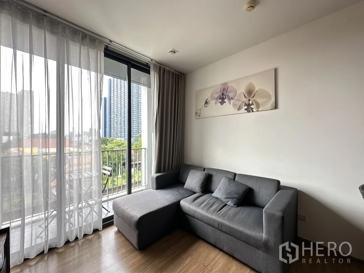 คอนโด for rent in Watthana, Bangkok - ห้องนั่งเล่นพร้อมโซฟาตัวแอลข้างผ้าม่านโปร่งติดระเบียง