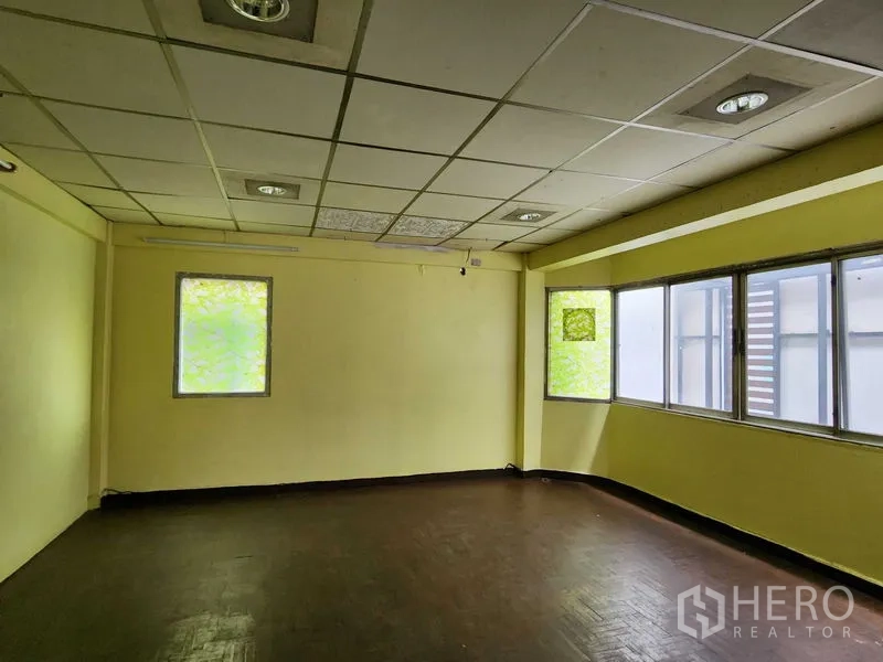 零售空间 出租在Bang Rak, Bangkok - 空置零售房，黄色墙面，吊顶嵌灯，大窗户引入充足自然光。