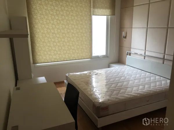 Condominium for rent in Sathon, Bangkok - Bright bedroom with padded headboard, queen bed, roller blinds and a built-in desk on light wood flooring in a Sathon condo.