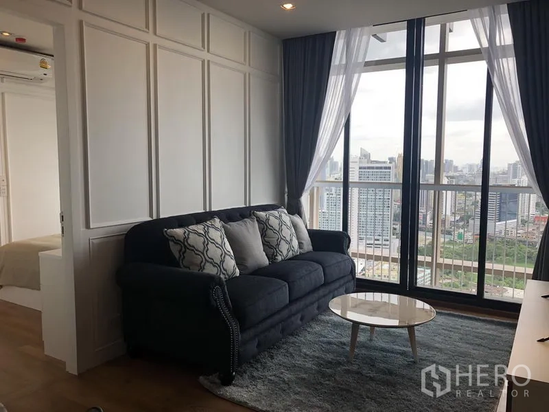 Condominium for rent in Khlong Toei, Bangkok - Living room with floor-to-ceiling windows and sweeping Bangkok skyline view.