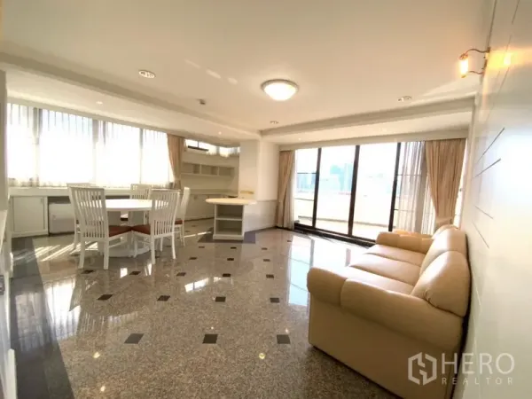 公寓 出租或出售在Watthana, Bangkok - 开放式客餐厅，花岗岩地面，沙发与餐桌，落地推拉门通往阳台。