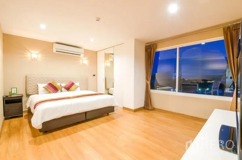 คอนโด ให้เช่าในKhlong Toei, Bangkok - ห้องนอนกว้างช่วงค่ำ มองเห็นวิวเมืองพร้อมโคมไฟผนัง ตู้กระจก และพื้นไม้