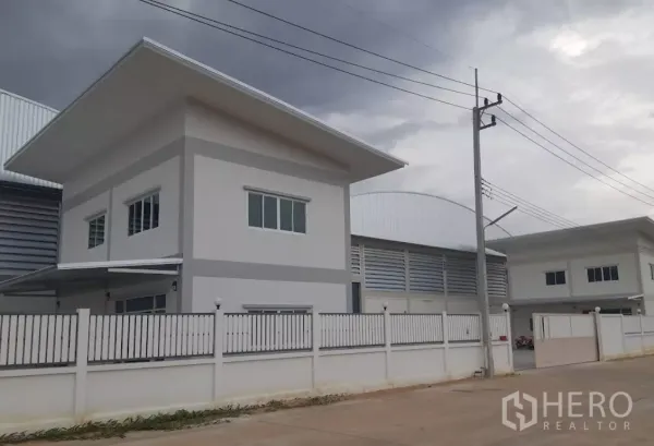 工厂 出租在Nakhon Pathom - 三攀工业园内带围栏的现代厂房与两层办公楼，临宽阔道路，阴天景色。