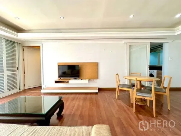 Condominium for rent - Open-plan lounge with wall-mounted TV and round dining set beside sliding doors.