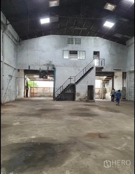 Warehouse for rent in Phra Samut Chedi, Samut Prakan - Open warehouse hall featuring a mezzanine office and metal staircase under a high gable roof.