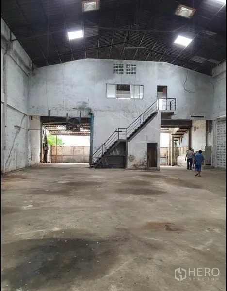 Warehouse for rent in Phra Samut Chedi, Samut Prakan - Open warehouse hall featuring a mezzanine office and metal staircase under a high gable roof.