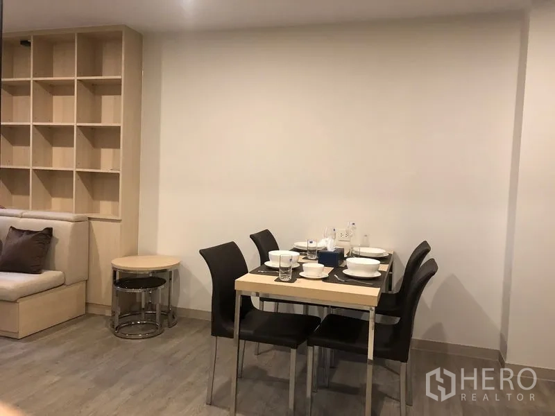 Condominium for rent or sale in Yan Nawa, Bangkok - Dining space with a four-seat table beside the open living area and shelving unit.