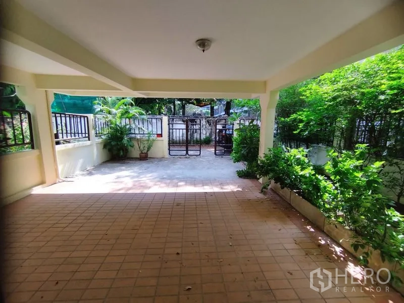 บ้าน ให้เช่าในWatthana, Bangkok - พื้นที่จอดรถมีหลังคามองไปยังประตูรั้วและกระบะต้นไม้