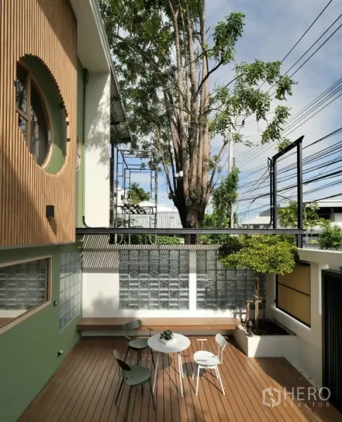 ทาวน์เฮาส์ ให้เช่าในWatthana, Bangkok - ลานระเบียงไม้หน้าบ้าน มีม้านั่ง ชุดโต๊ะเก้าอี้ และต้นไม้เล็ก ข้างผนังกระจกบล็อก