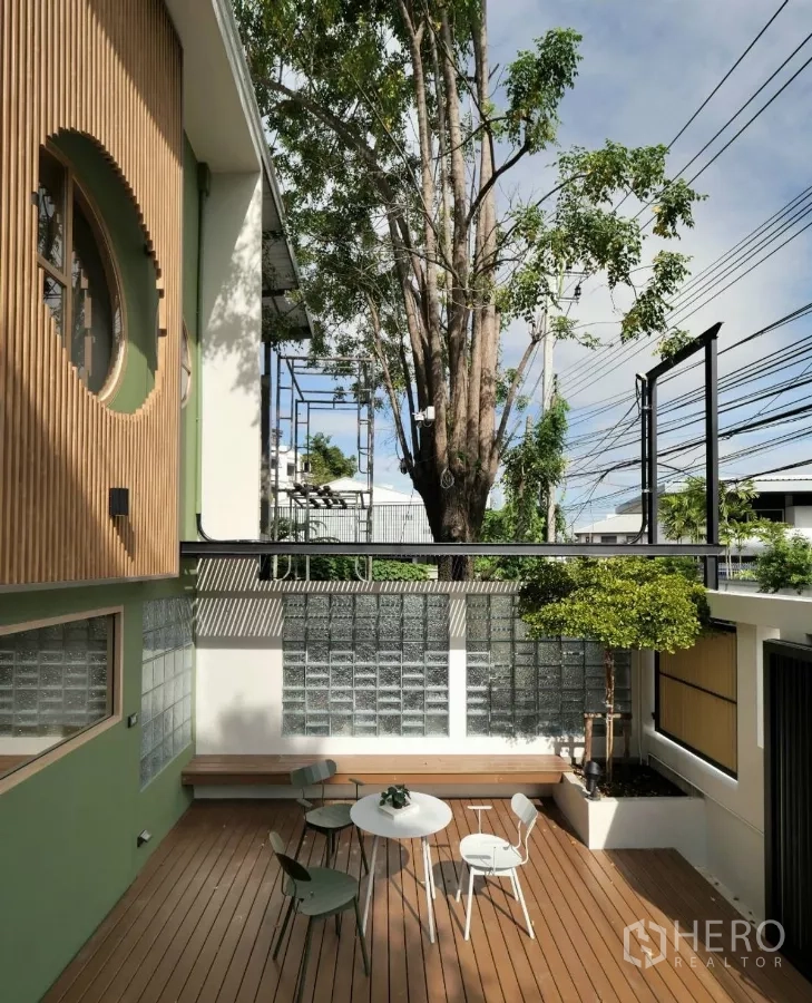 ทาวน์เฮาส์ ให้เช่าในWatthana, Bangkok - ลานระเบียงไม้หน้าบ้าน มีม้านั่ง ชุดโต๊ะเก้าอี้ และต้นไม้เล็ก ข้างผนังกระจกบล็อก