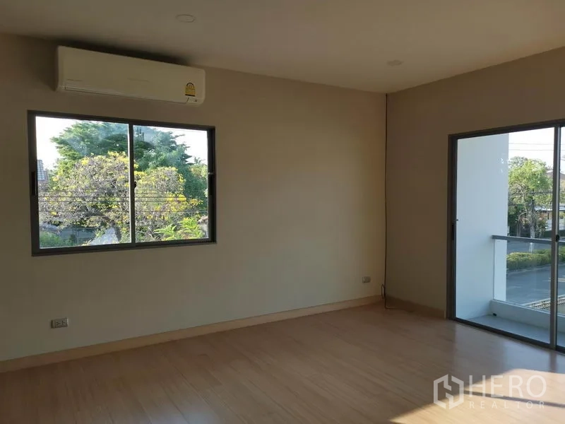 Detached House for sale in Nonthaburi - Bedroom with air conditioner, window views of trees and access to the balcony.