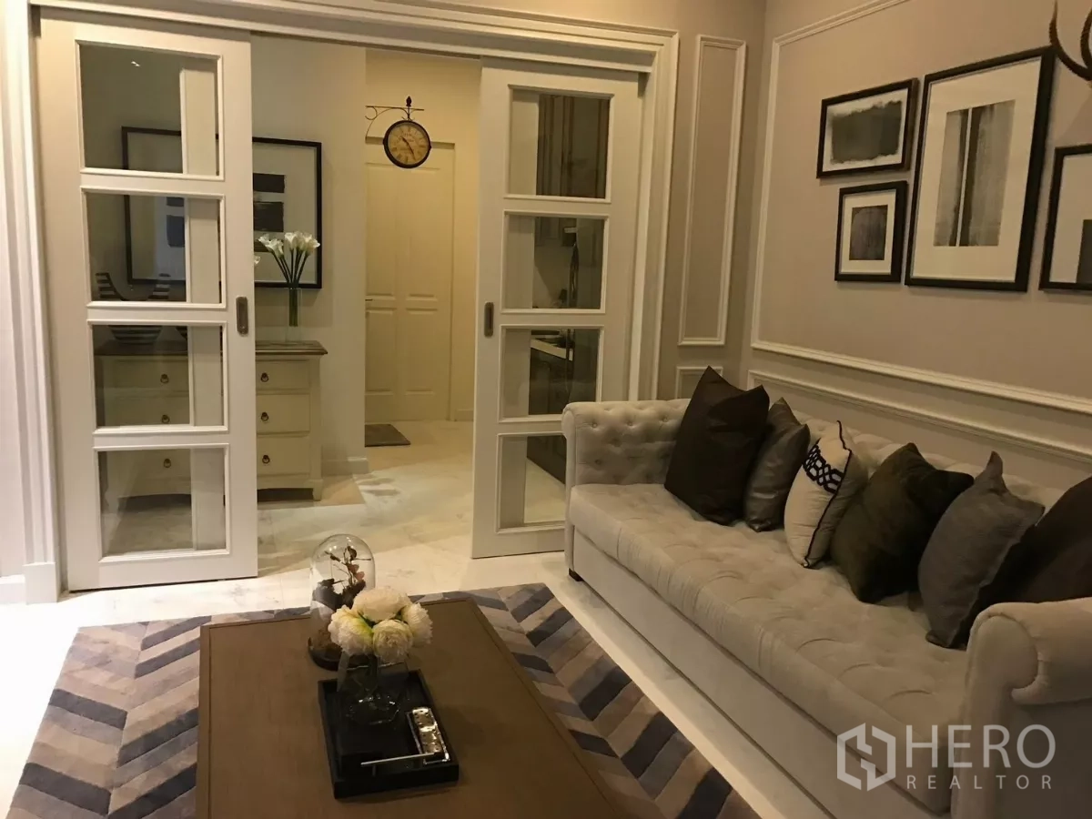 Townhouse for sale in Watthana, Bangkok - Living room with tufted sofa, chevron rug and white sliding glass doors.