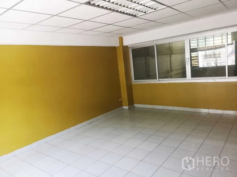 Factory for sale in Khlong Luang, Pathum Thani - Yellow-walled office overlooking the warehouse through a large internal window.