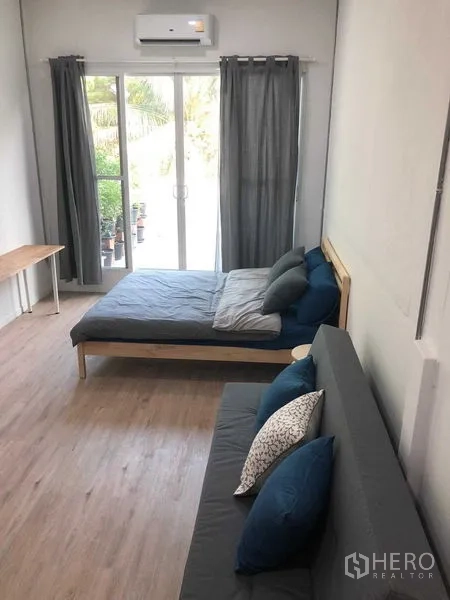 Detached House for rent in Phra Nakhon, Bangkok - Air-conditioned bedroom with a bed and sofa, sliding glass doors opening to greenery.