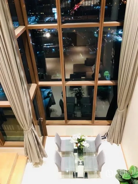 คอนโด ให้เช่าในKhlong Toei, Bangkok - พื้นที่นั่งเล่นและรับประทานอาหารเพดานสูง พร้อมหน้าต่างกระจกสูงจรดเพดาน วิวเมืองยามค่ำ ในคอนโดคลองเตย กรุงเทพฯ