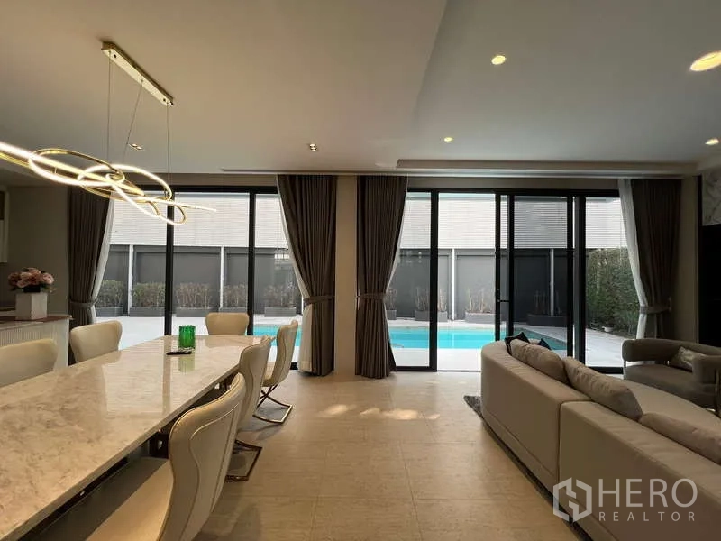 独立式住宅 出租在Suan Luang, Bangkok - 明亮餐厅，大理石餐桌与设计吊灯，可直达泳池