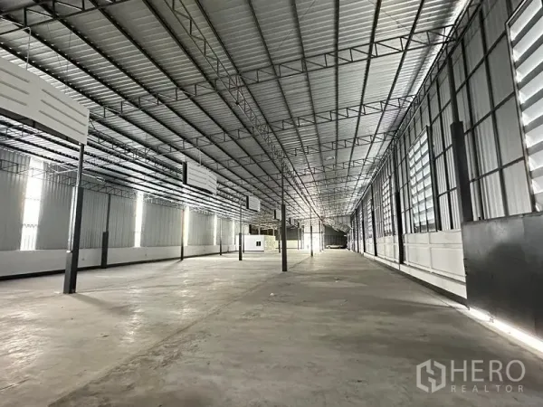 货栈 出租在Khan Na Yao, Bangkok - 明亮仓库通道，百叶通风窗、混凝土地面与大跨屋顶。
