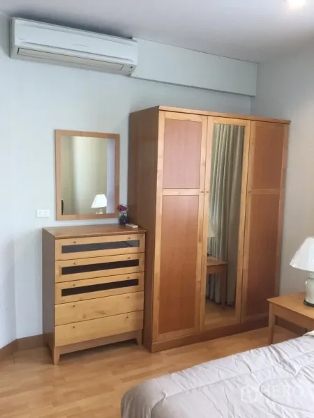 คอนโด ให้เช่าในKhlong Toei, Bangkok - มุมห้องนอนพร้อมตู้เสื้อผ้าไม้ โต๊ะลิ้นชัก และเครื่องปรับอากาศ
