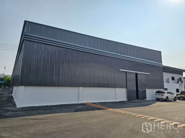 货栈 出租在Khlong Toei, Bangkok - 仓库正立面，超高推拉装卸门，旁有停车位。