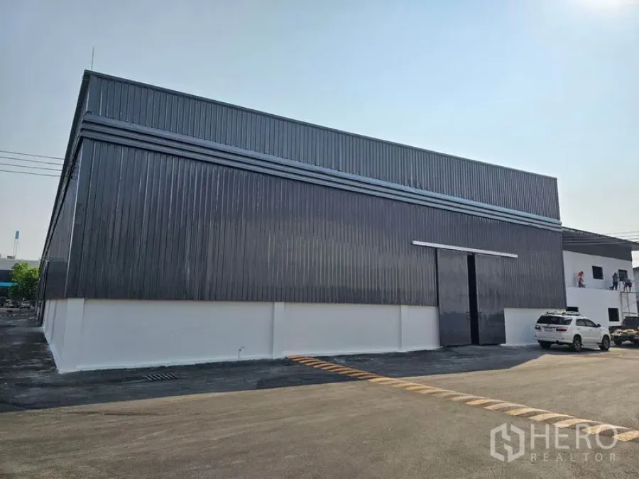 货栈 出租在Khlong Toei, Bangkok - 仓库正立面，超高推拉装卸门，旁有停车位。