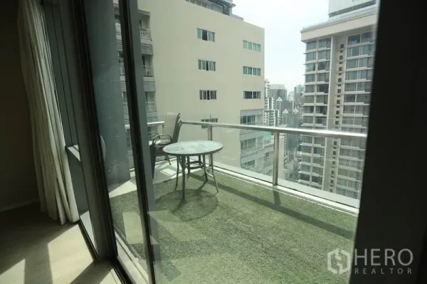 Condominium for rent or sale in Watthana, Bangkok - Private balcony with glass railing, artificial grass flooring, and open city view between towers.