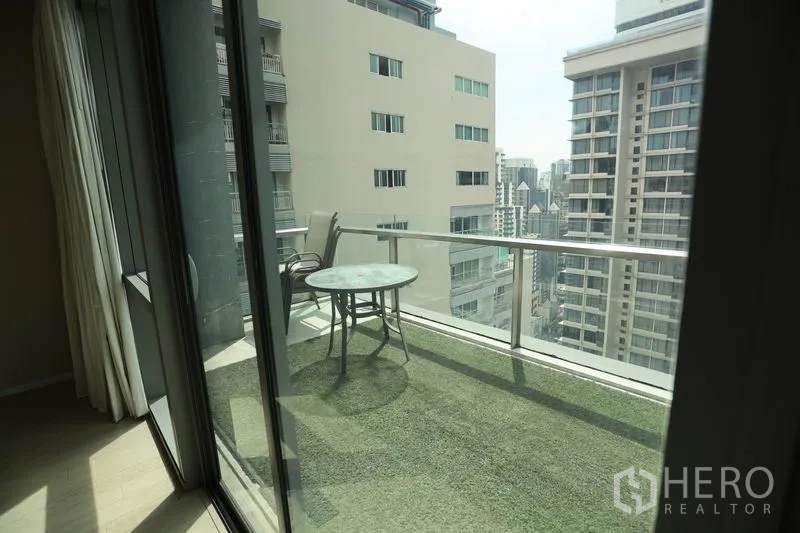 Condominium for rent or sale in Watthana, Bangkok - Private balcony with glass railing, artificial grass flooring, and open city view between towers.