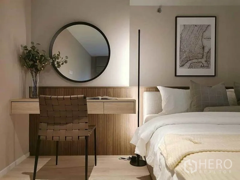 公寓 出租在Bang Rak, Bangkok - 极简卧室，内置书桌、圆镜与柔和灯光的整洁床品。