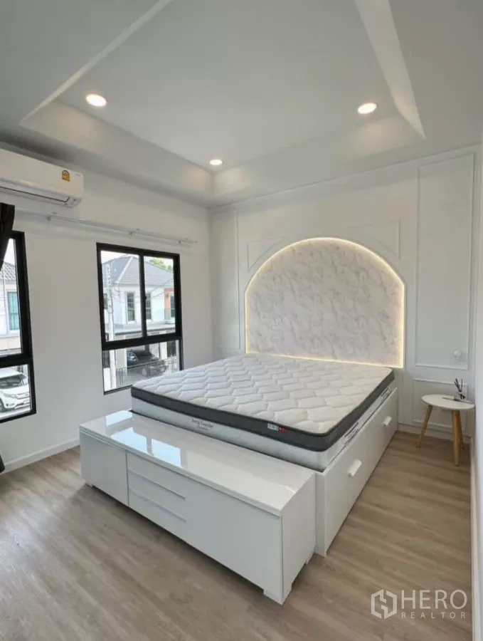 บ้าน ให้เช่าหรือขายในKhlong Toei, Bangkok - ห้องนอนหลัก หน้าต่างบานใหญ่ หัวเตียงโค้งไฟ LED พื้นไม้และไฟดาวน์ไลท์.