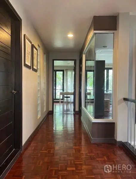 Townhouse for rent in Phaya Thai, Bangkok - Upper-floor corridor with polished parquet, built-in glass display and windowed room ahead.