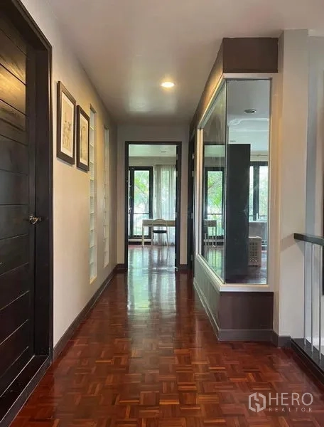 Townhouse for rent in Phaya Thai, Bangkok - Upper-floor corridor with polished parquet, built-in glass display and windowed room ahead.