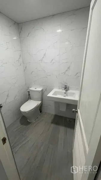 联排别墅 出售在Prawet, Bangkok - 干净浴室，仿大理石墙砖、坐便器与洗手盆。