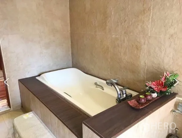 Detached House for sale in Saphan Sung, Bangkok - Bathroom with built-in soaking tub, beige wall tiles and wooden trim.