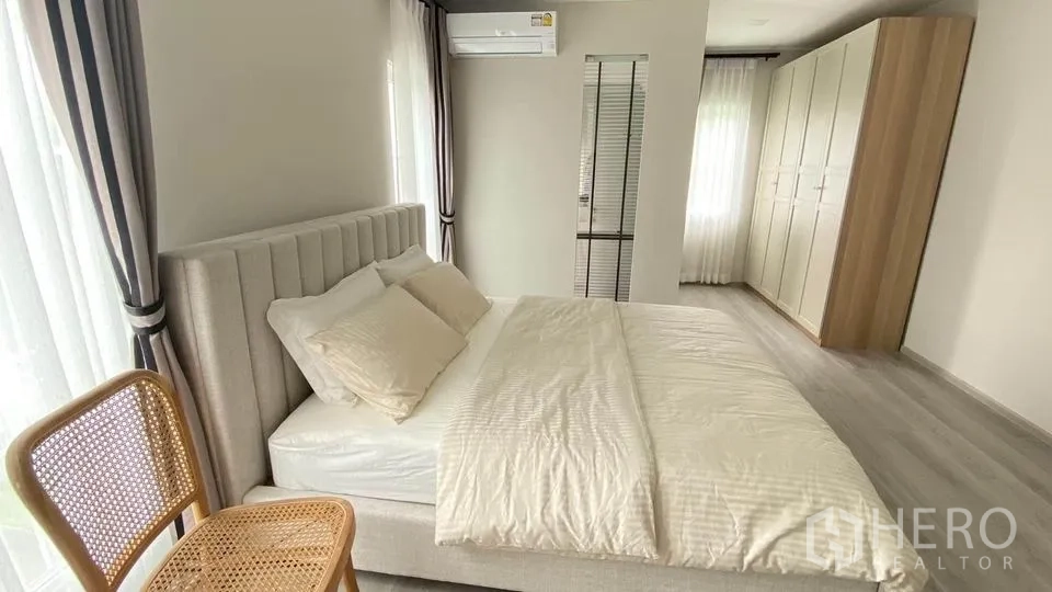 联排别墅 出租在Prawet, Bangkok - 一楼多功能房，通过推拉门连接花园，灰色地板与边柜。