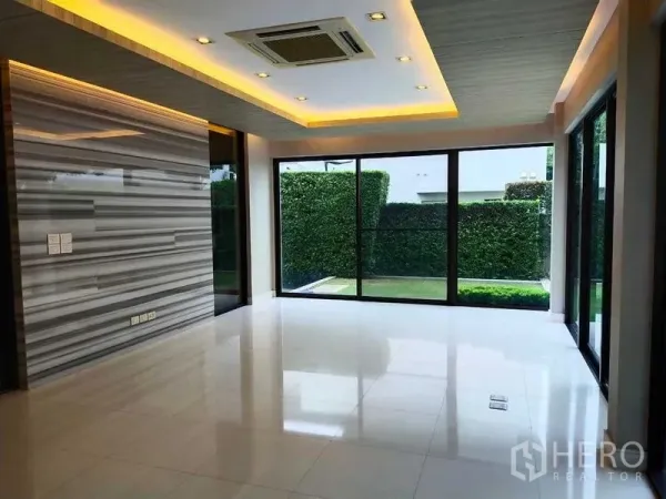 独立式住宅 出租或出售在Mueang Nonthaburi, Nonthaburi - 客厅敞阔，带大理石纹特色墙、筒灯与通向花园的推拉玻璃门。