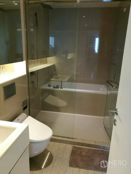 Condominium for rent in Watthana, Bangkok - Modern bathroom with glass-enclosed shower and bathtub, wall-mounted toilet and vanity in a Watthana Bangkok condo.