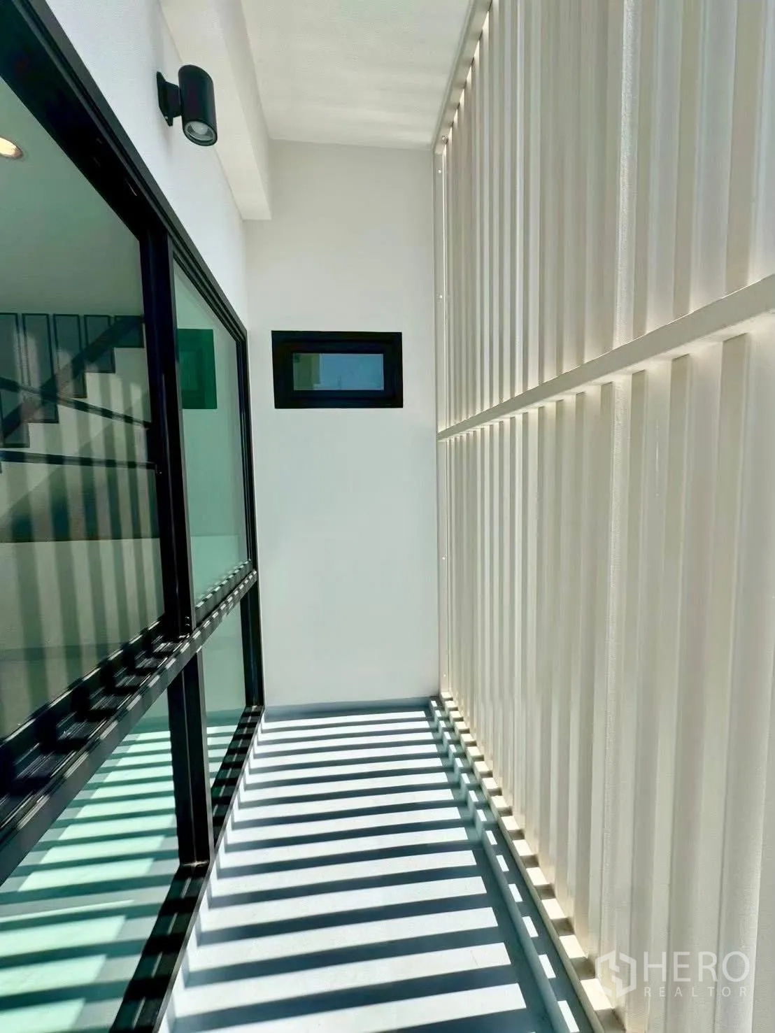 Home Office for rent in Wang Thonglang, Bangkok - Slim balcony with privacy screen slats and wall light outside glass doors.