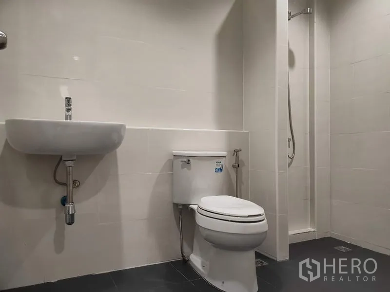 Home Office for sale in Lam Luk Ka, Pathum Thani - Clean bathroom with toilet, wall-hung sink and shower area.