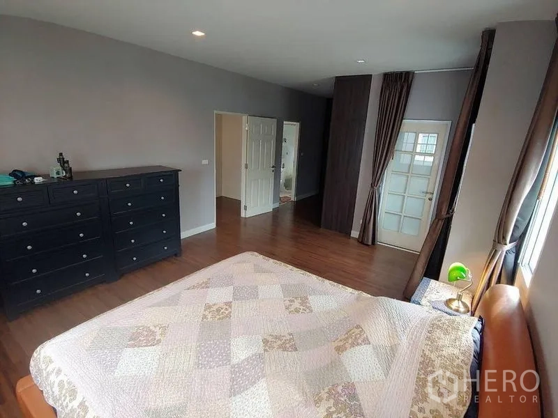 Detached House for sale in Khlong Sam Wa, Bangkok - Generous master bedroom with large windows, dresser, and wooden floors.