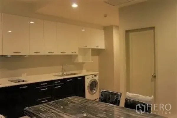 คอนโด ให้เช่าในWatthana, Bangkok - ครัวคอนโดสไตล์โมเดิร์น ตู้บนสีขาว ตู้ล่างสีดำ อ่างล้างจาน เตา และเครื่องซักผ้าหน้าตรงข้างโต๊ะกินข้าวหินอ่อน