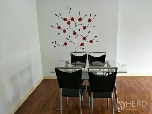 公寓 出租在Khlong Toei, Bangkok - 餐区配玻璃餐桌和四把黑色椅子，白墙上有花卉墙贴