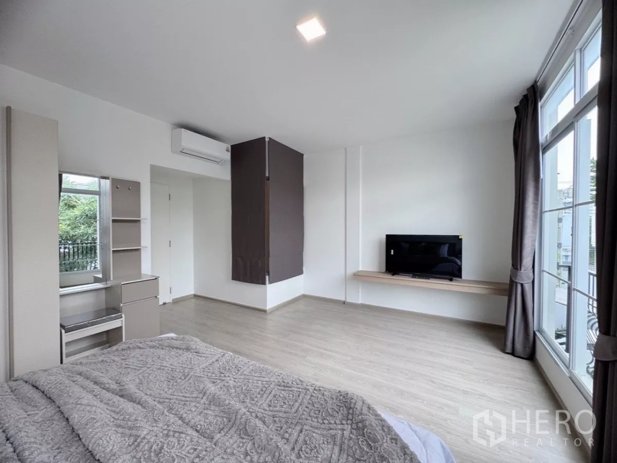 联排别墅 出租在Prawet, Bangkok - 宽敞主卧，电视搁架与整面落地窗。