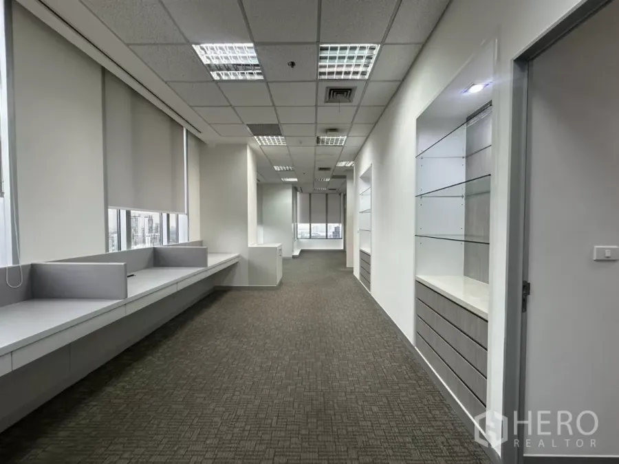 办公空间 出租在Watthana, Bangkok - 铺地毯的办公室走廊，带内置工作台、卷帘与城市景观。