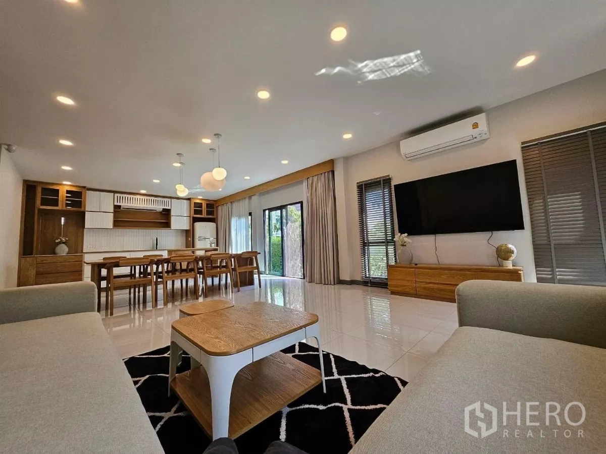 Detached House for rent or sale in Bang Phli, Samut Prakan - Bright living and dining area with sofa set, long dining table, media wall, and sliding glass doors to the yard.