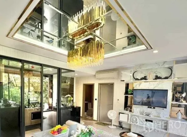 คอนโด ขายในWatthana, Bangkok - ห้องนั่งเล่นเพดานกระจกพร้อมโคมไฟระย้าสีทอง ผนังทีวีหินอ่อน และประตูกระจกสไลด์