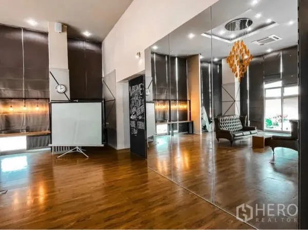 Office Space for rent in Lak Si, Bangkok - Open-plan 80 sqm Bangkok office with mirrored wall, high ceilings, wooden floors, leather sofas, projector screen and pendant chandelier by tall windows with blinds.