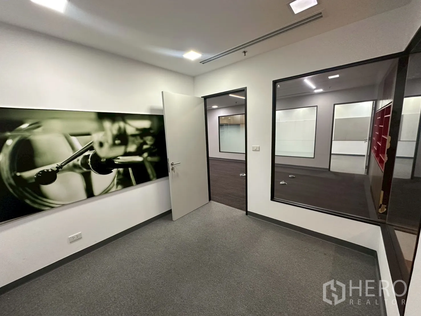 Office Space for rent - Private room with interior glass window and monochrome wall art.