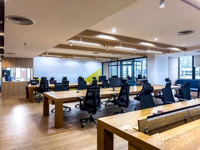 办公室 for rent in Bang Rak, Bangkok - 开放工位区，长条木桌、人体工学椅与窗户采光。