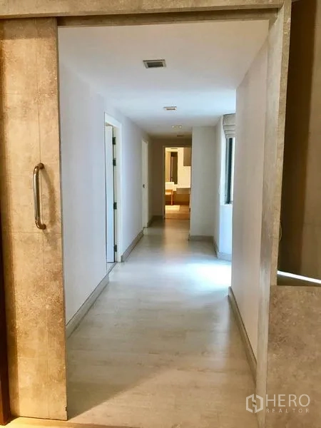 Condominium for rent or sale in Watthana, Bangkok - Long hallway with sliding door and light wood flooring connecting rooms.