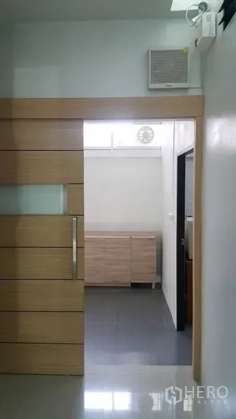 Shophouse for rent in Khan Na Yao, Bangkok - Interior view of corridor with modern wooden sliding door and a low storage cabinet beyond.