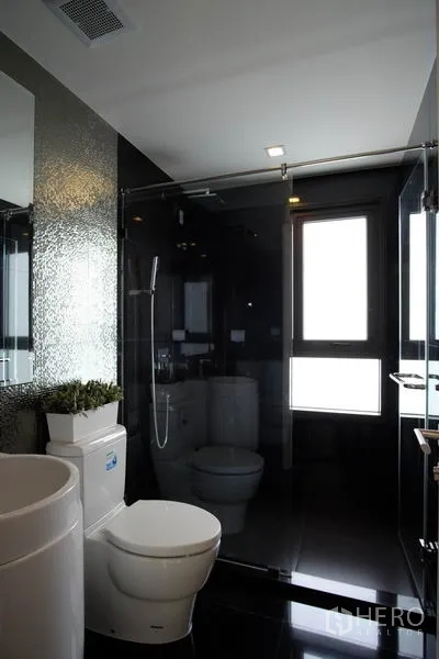 Condominium for rent in Khlong Toei, Bangkok - Second bathroom featuring a glass-enclosed shower, toilet and window for natural light.